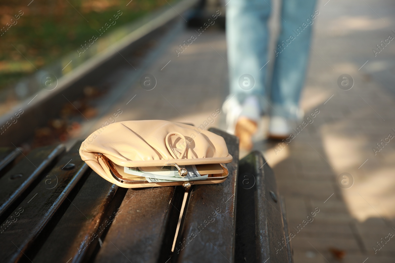 Photo of Woman lost her purse on wooden surface outdoors, selective focus