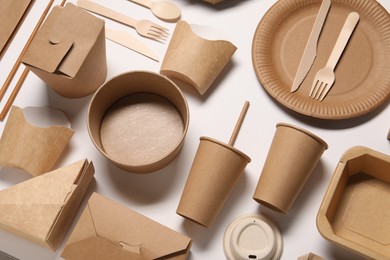 Photo of Eco friendly food packaging. Paper containers and tableware on white background, above view