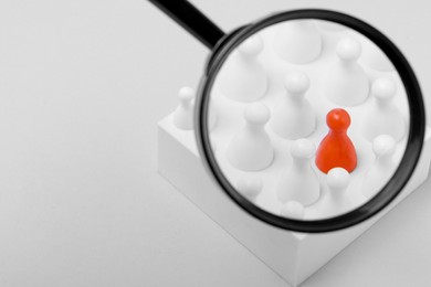 Photo of Magnifying glass over pawns on white background, space for text. Recruiter searching employee