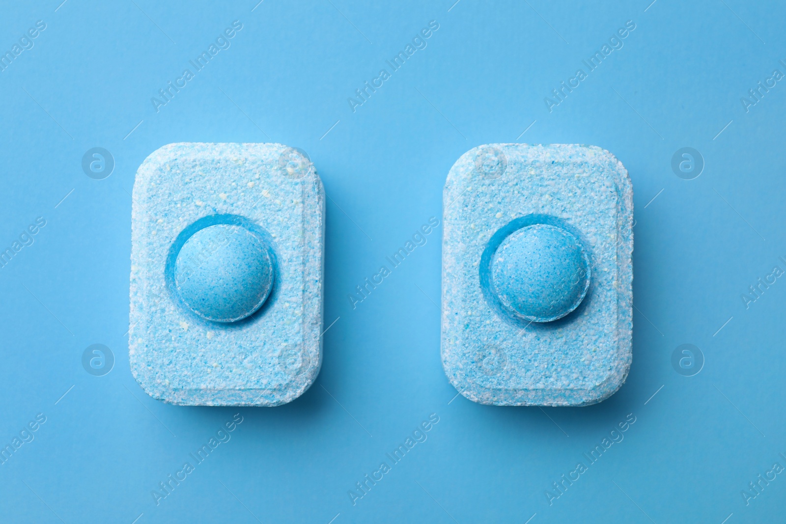 Photo of Water softener tablets on light blue background, flat lay