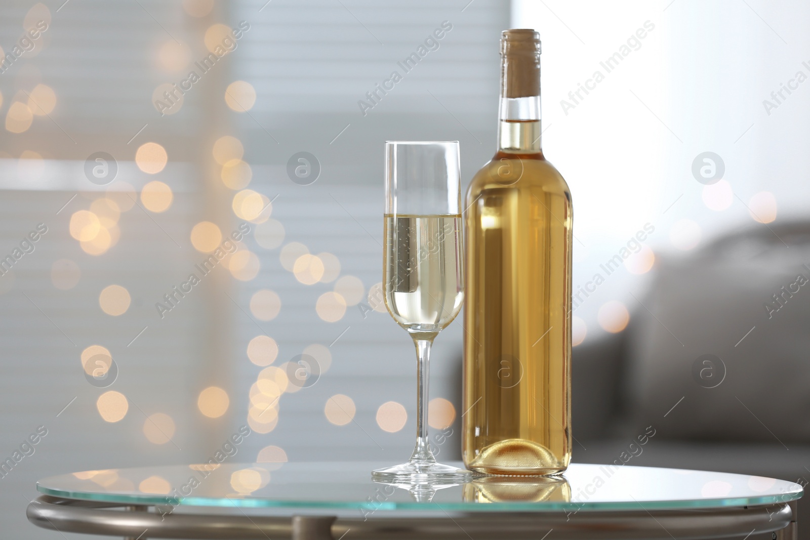 Photo of Glass and bottle with delicious wine on table indoors, space for text