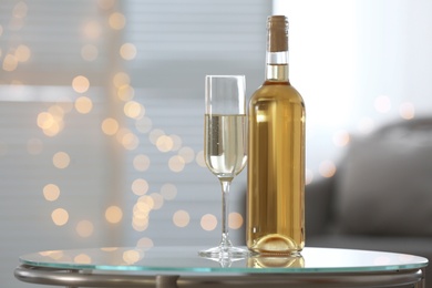 Photo of Glass and bottle with delicious wine on table indoors, space for text