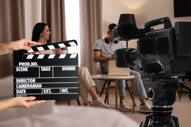 Image of Shooting movie. Second assistant camera holding clapperboard near video camera in front of couple (actors) at hotel (film set)