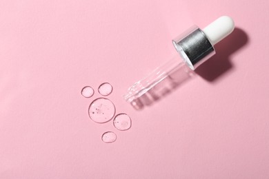 Clear cosmetic serum and pipette on pink background, top view