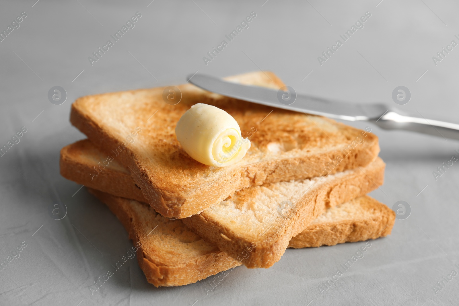 Photo of Toasted bread with butter curl on table