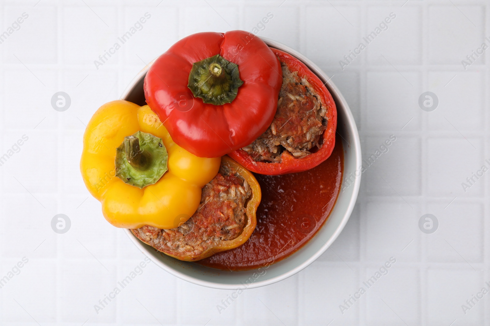 Photo of Delicious stuffed bell peppers on white tiled table, top view