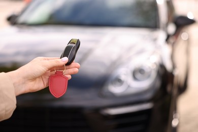 Photo of Woman holding car flip key near her vehicle outdoors, closeup