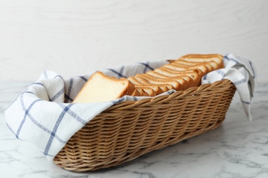 Slices of bread in basket on white marble table