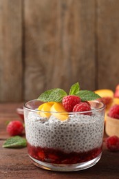 Delicious chia pudding with raspberries, peach and mint on wooden table, space for text