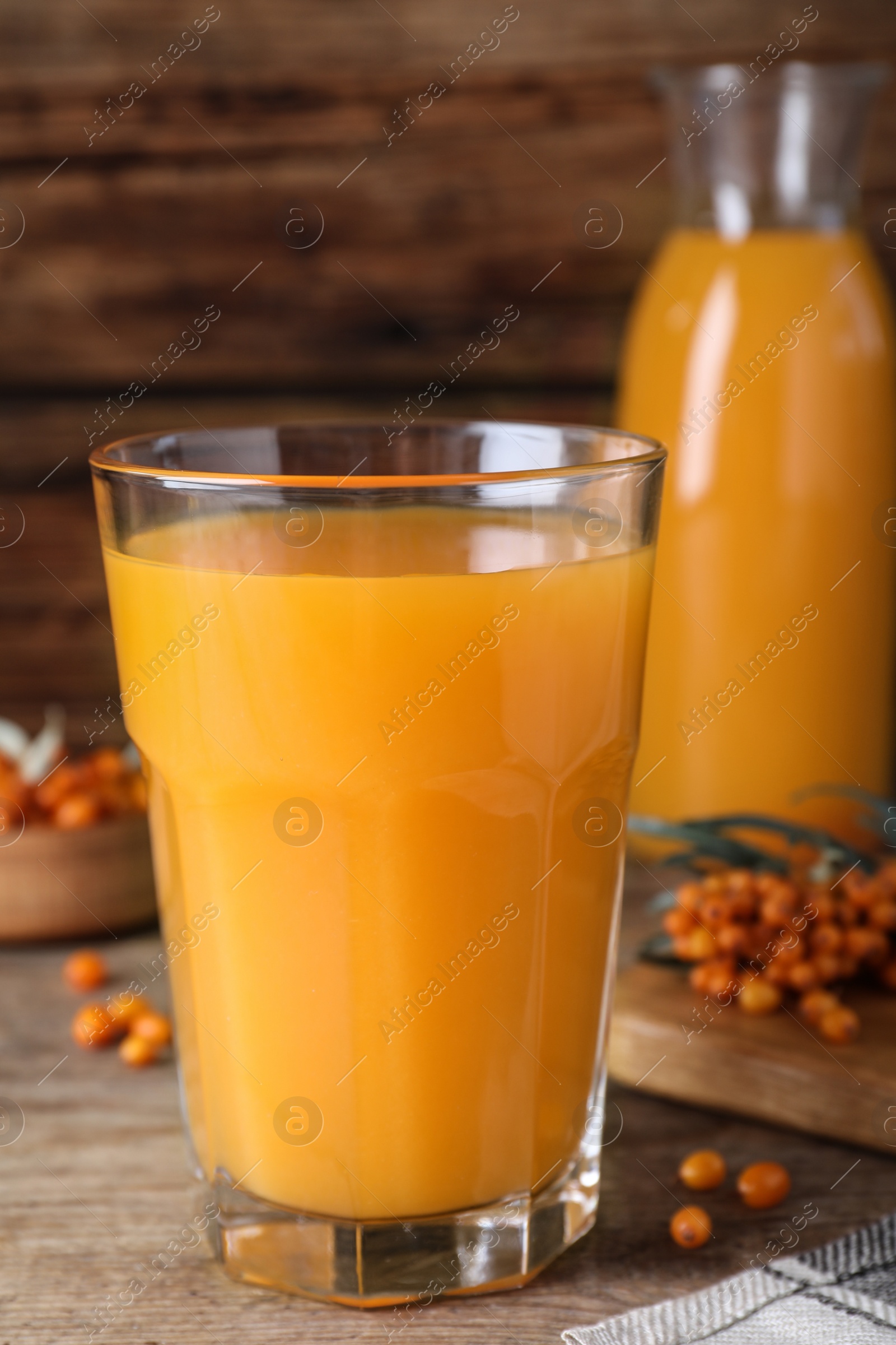 Photo of Delicious sea buckthorn juice on wooden table, closeup