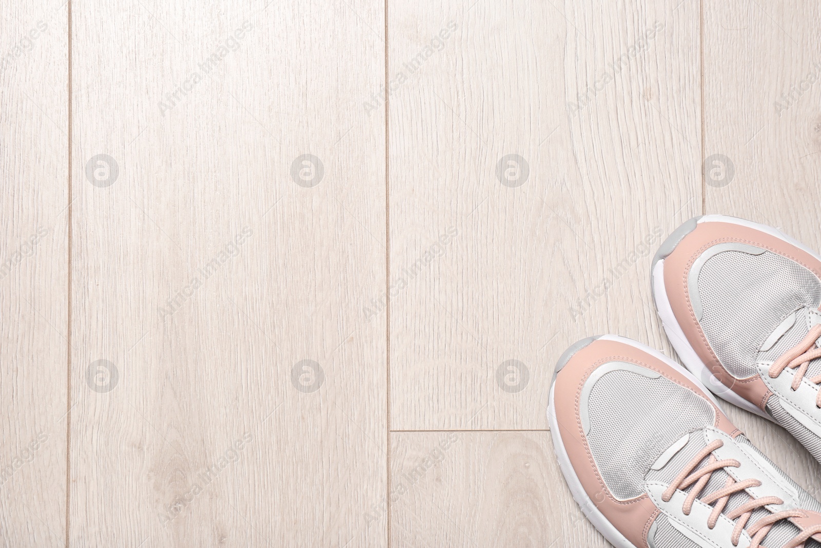 Photo of Pair of sport shoes on wooden floor, top view with space for text