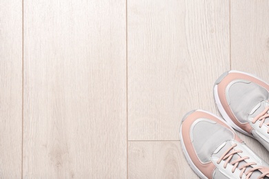 Pair of sport shoes on wooden floor, top view with space for text