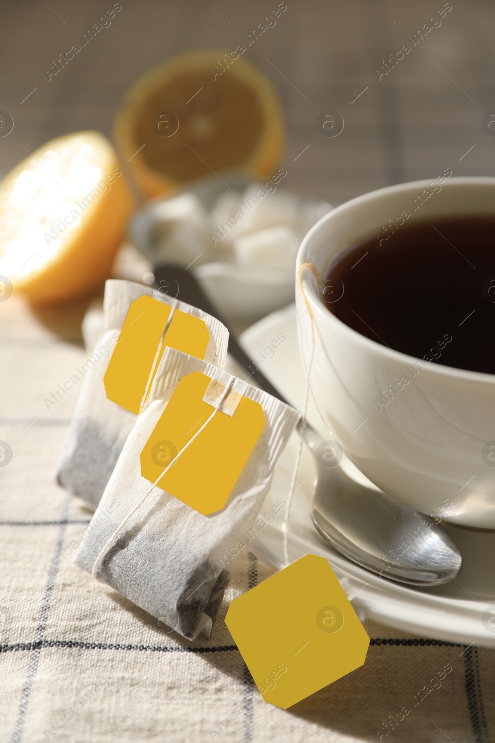 Photo of Tea bags near cup of hot drink on table, closeup