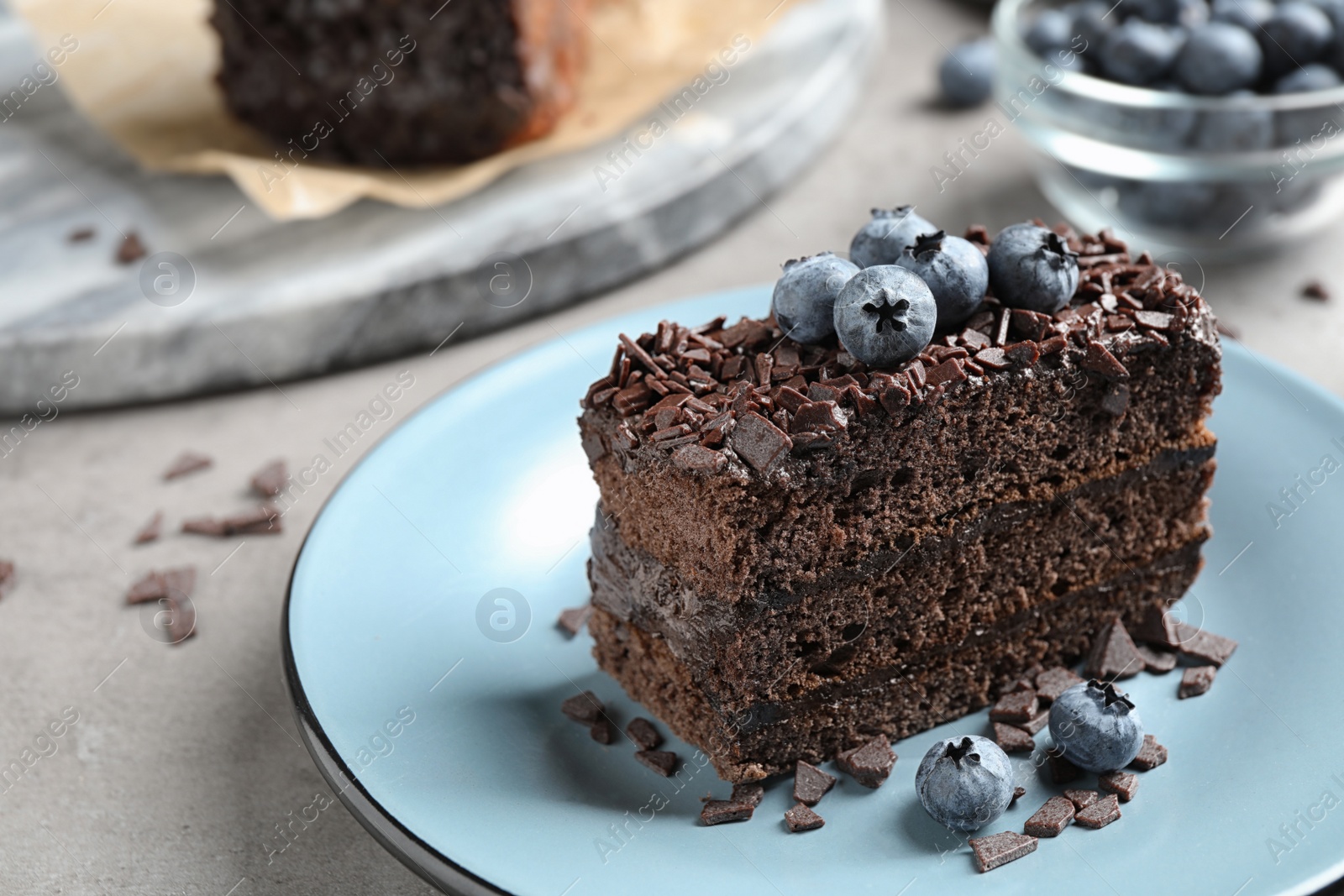 Photo of Delicious fresh chocolate cake with blueberries on light table, closeup