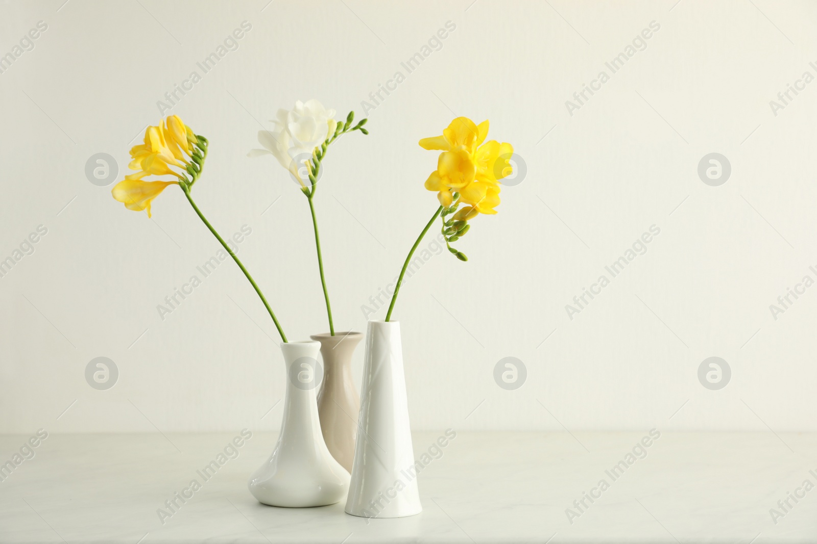 Photo of Beautiful freesia flowers on white marble table