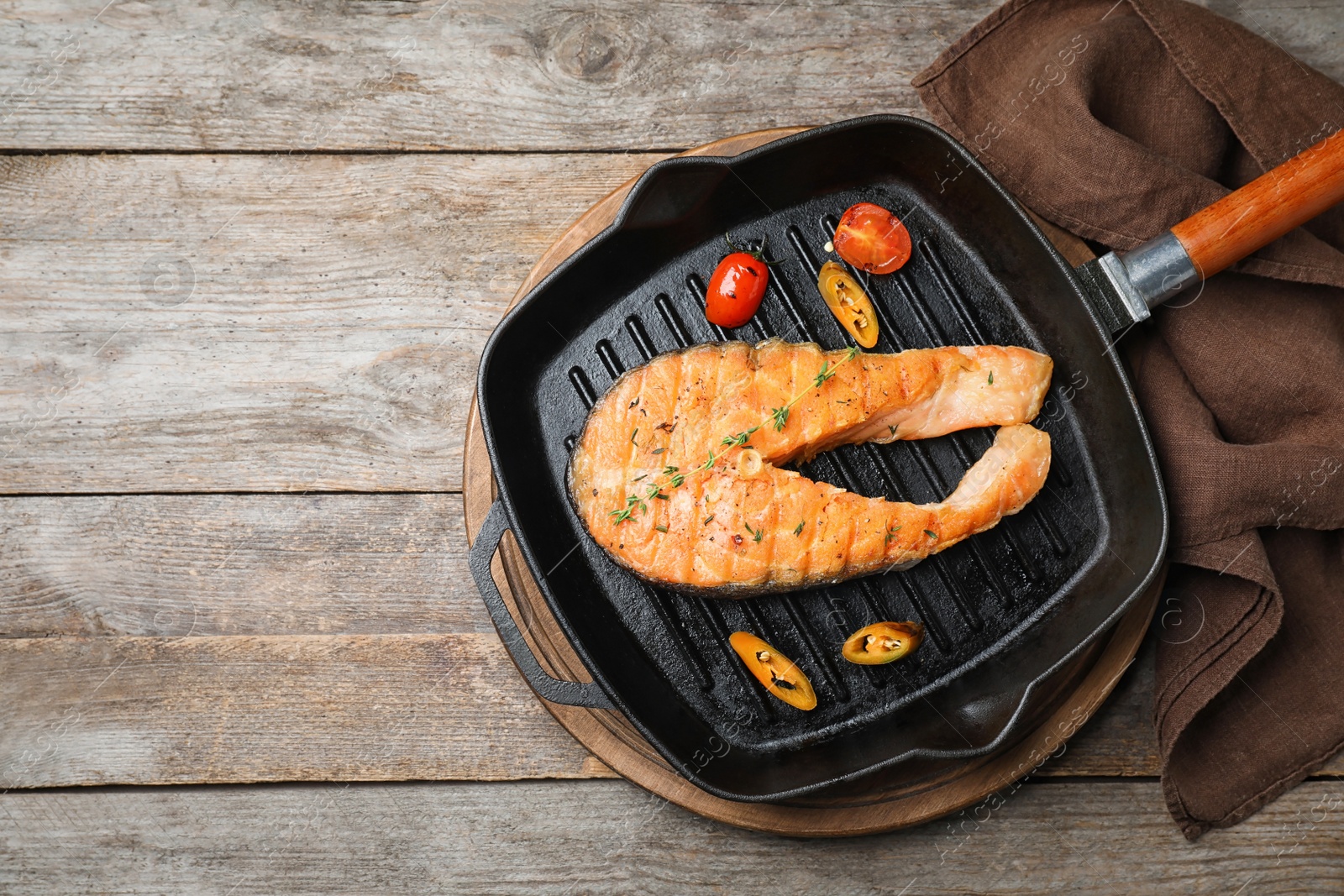 Photo of Frying pan with tasty salmon steak on wooden background