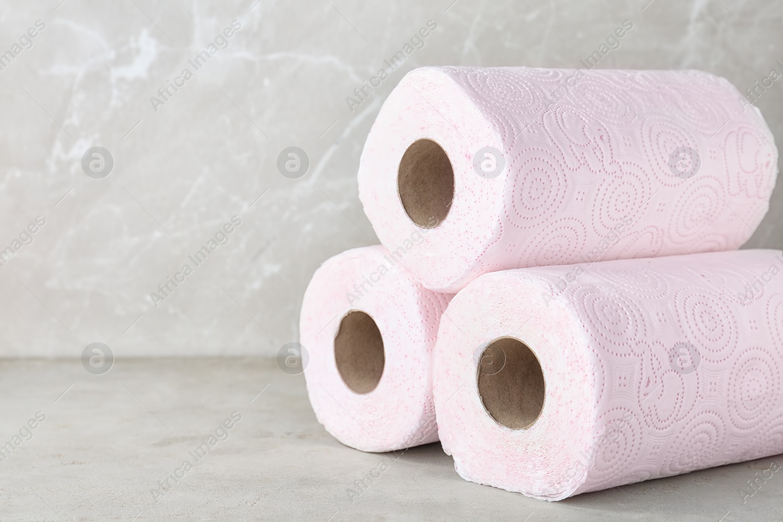 Photo of Rolls of toilet paper on grey table. Space for text