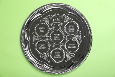 Photo of Passover Seder plate (keara) on light green background, top view. Pesah celebration