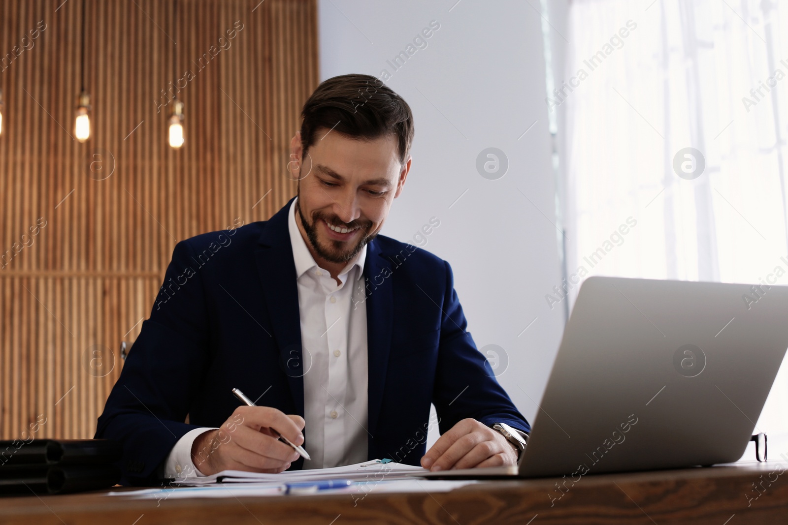 Photo of Businessman working with laptop and documents at table in office