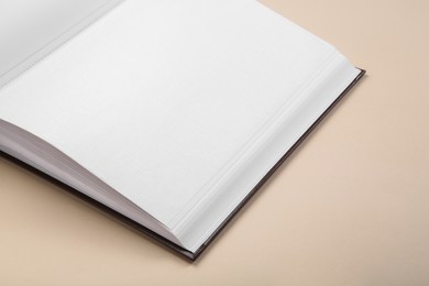 Photo of Open photo album on beige background, closeup. Space for text