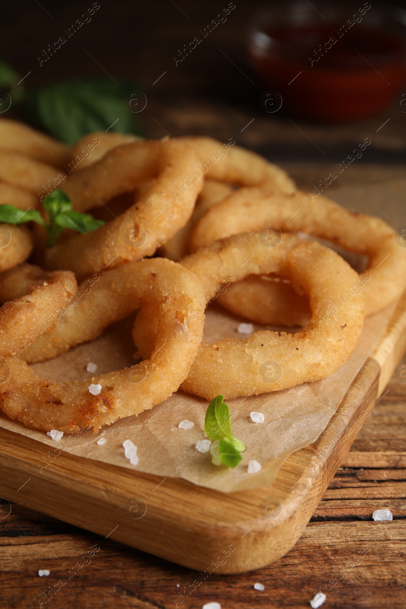 Photo of Delicious onion rings on wooden table, closeup