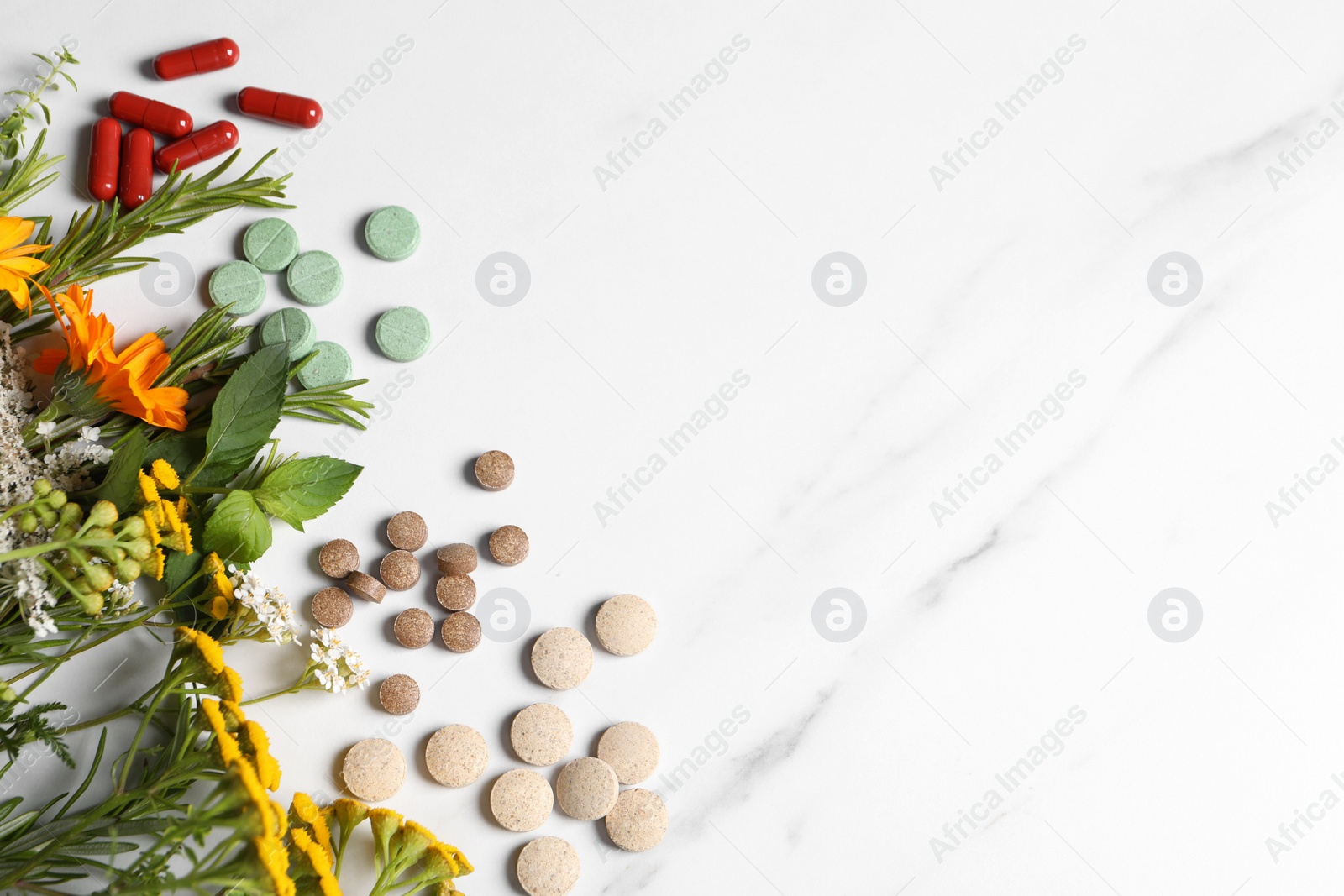 Photo of Different pills, herbs and flowers on white table, flat lay with space for text. Dietary supplements