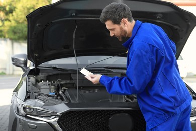 Photo of Worker checking motor oil level with dipstick outdoors