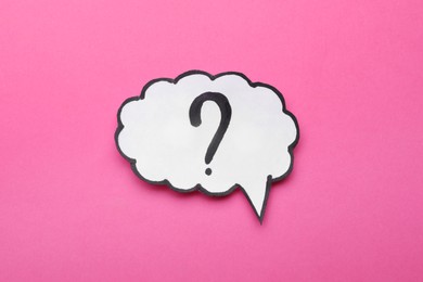 Paper speech bubble with question mark on pink background, top view