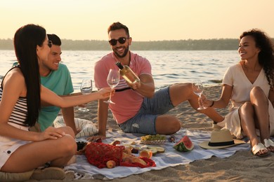 Photo of Group of friends having picnic outdoors at sunset