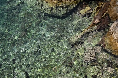 Photo of Shallow water with rocky sea bottom as background, top view