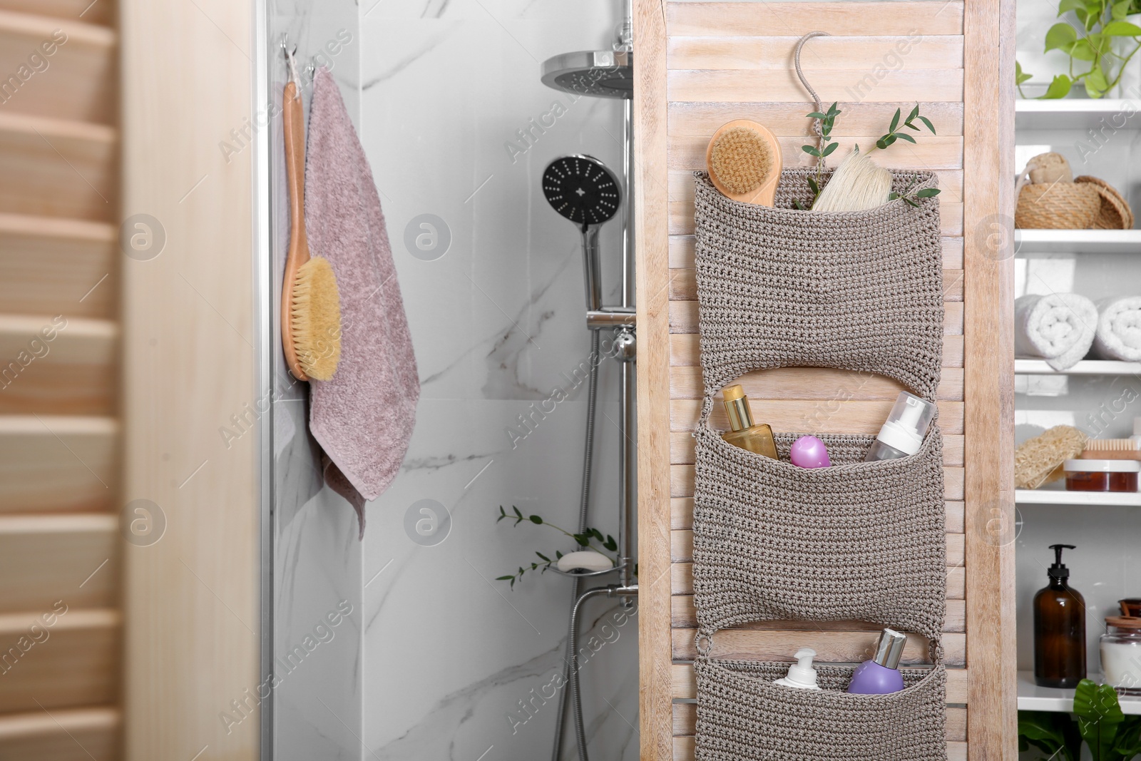 Photo of Knitted organizer hanging on wooden door in bathroom