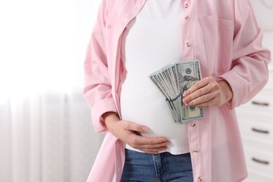 Surrogate mother. Pregnant woman with dollar banknotes indoors, closeup. Space for text