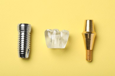 Parts of dental implant on yellow background, flat lay