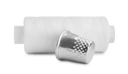 Photo of Thimble and spool of sewing thread isolated on white