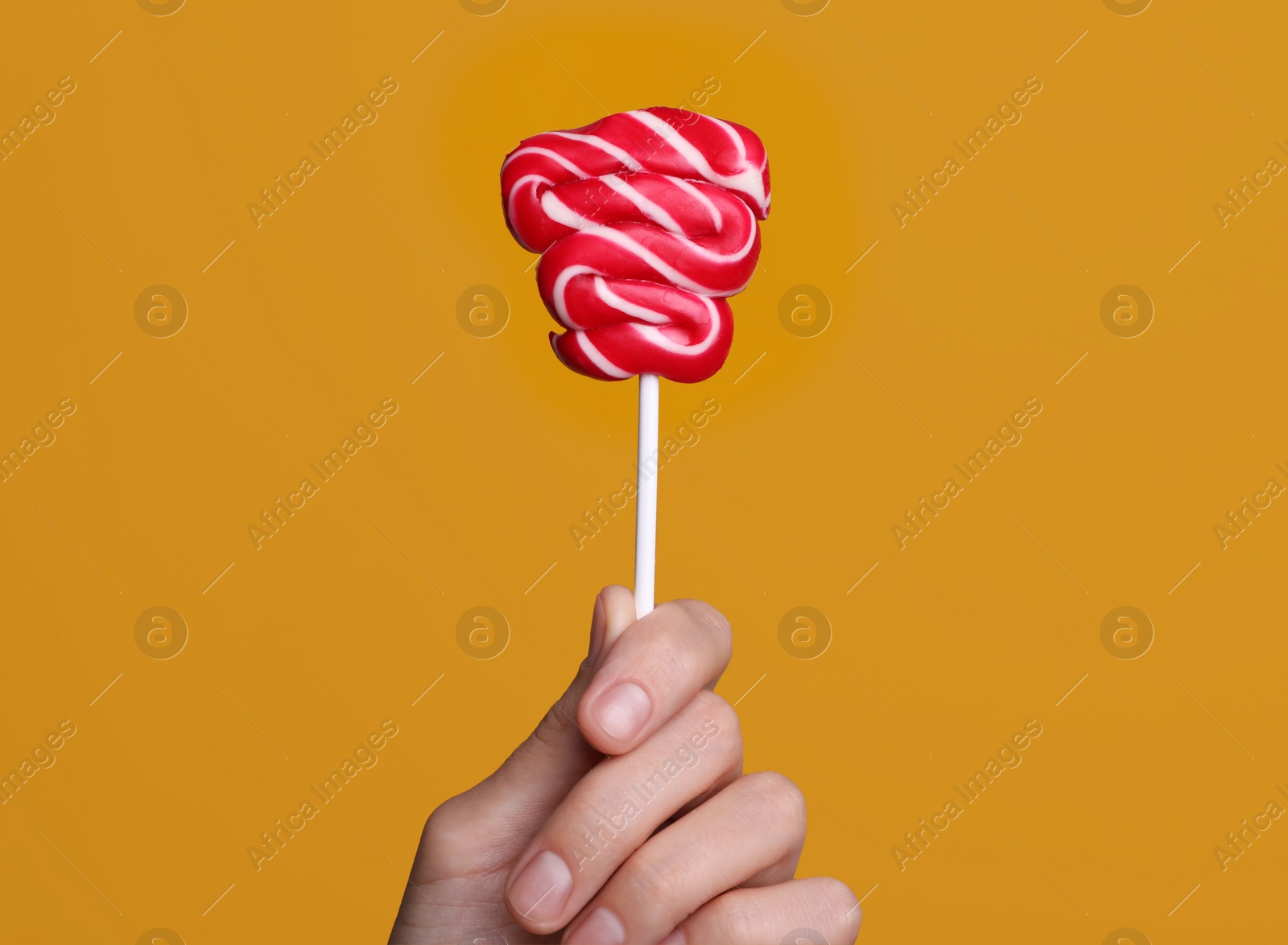 Photo of Woman holding bright tasty lollipop on orange background, closeup