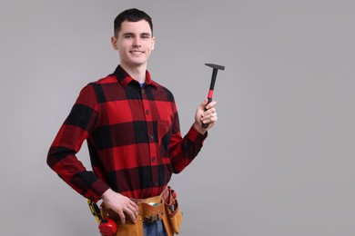 Professional repairman holding hammer on light grey background. Space for text