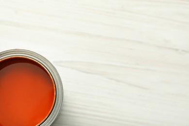 Photo of Can of orange paint on white wooden table, top view. Space for text