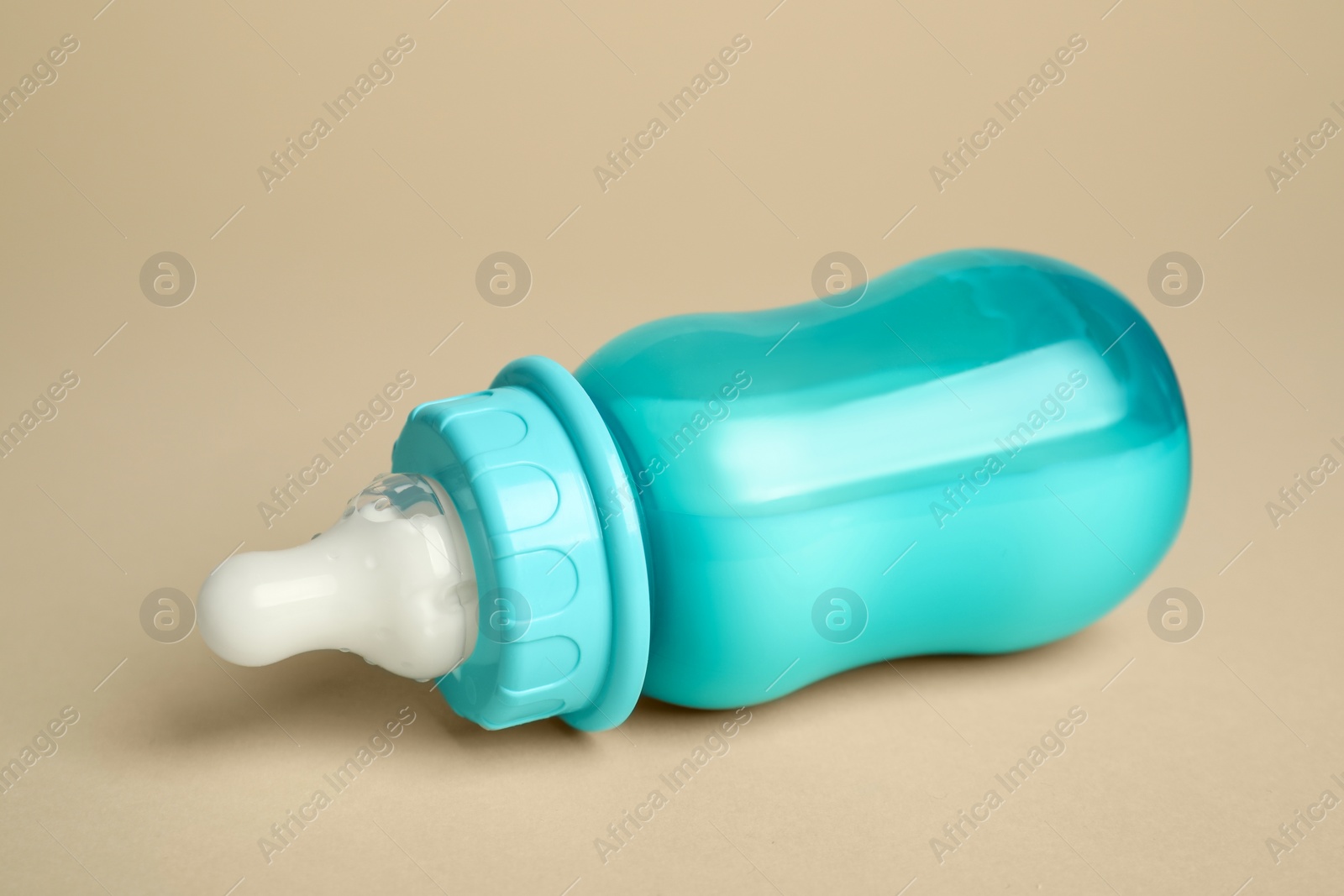 Photo of Feeding bottle with baby formula on beige background