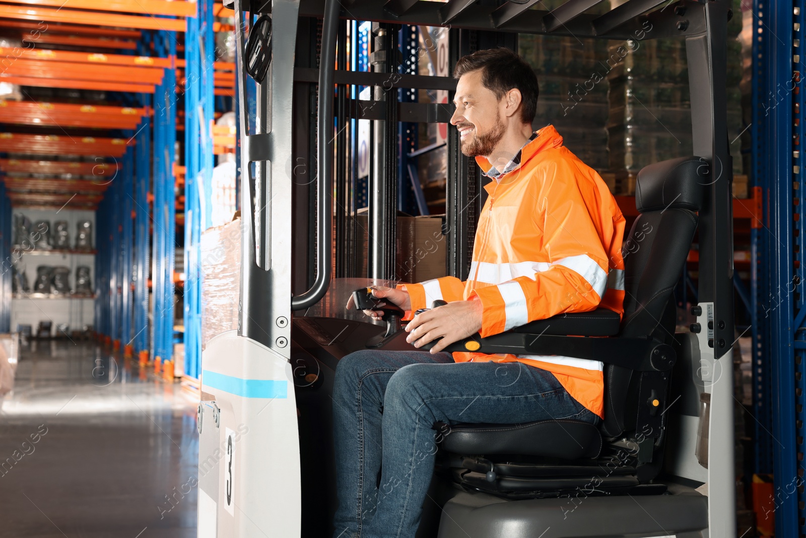 Photo of Happy worker sitting in forklift truck at warehouse