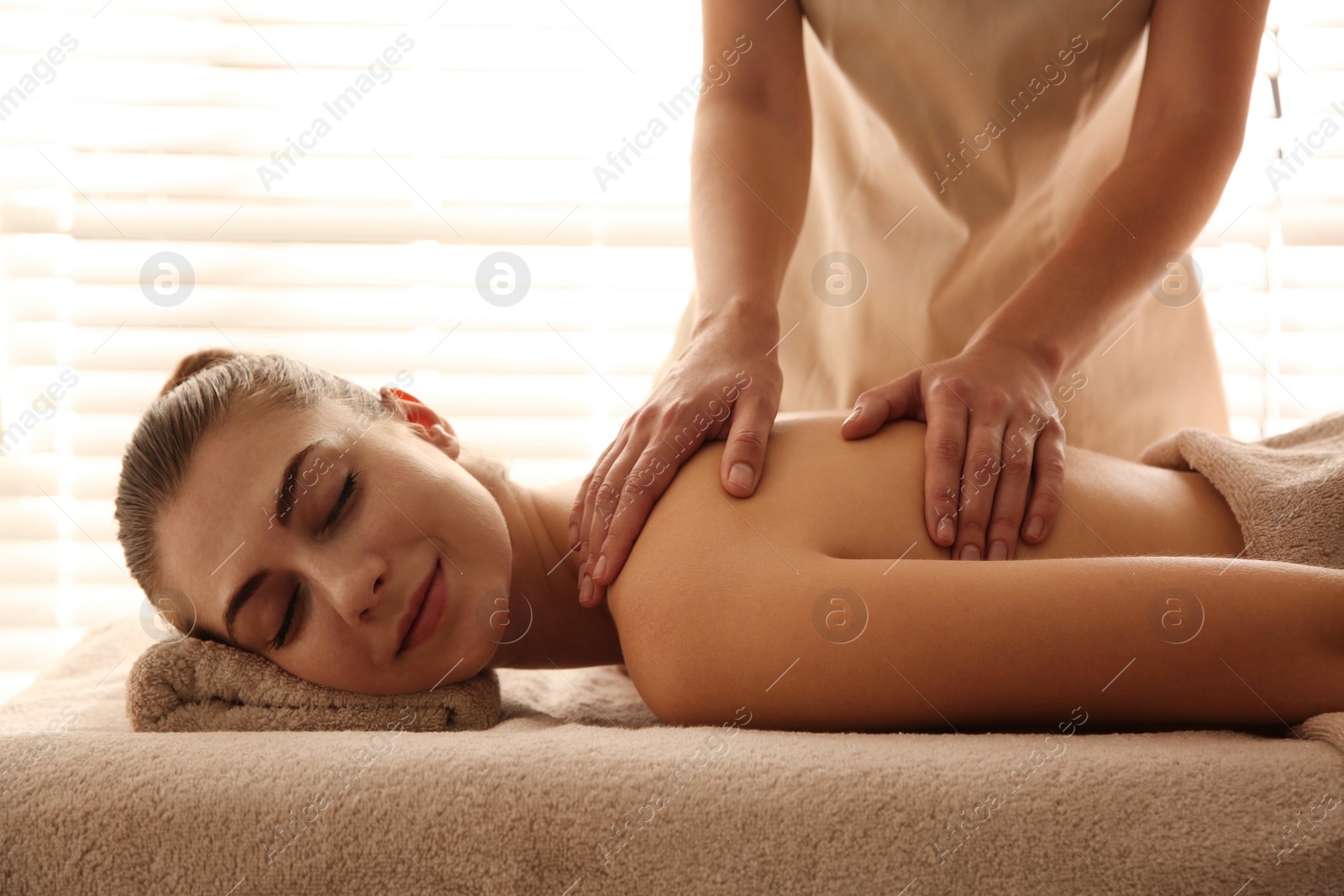 Photo of Young woman receiving back massage in spa salon