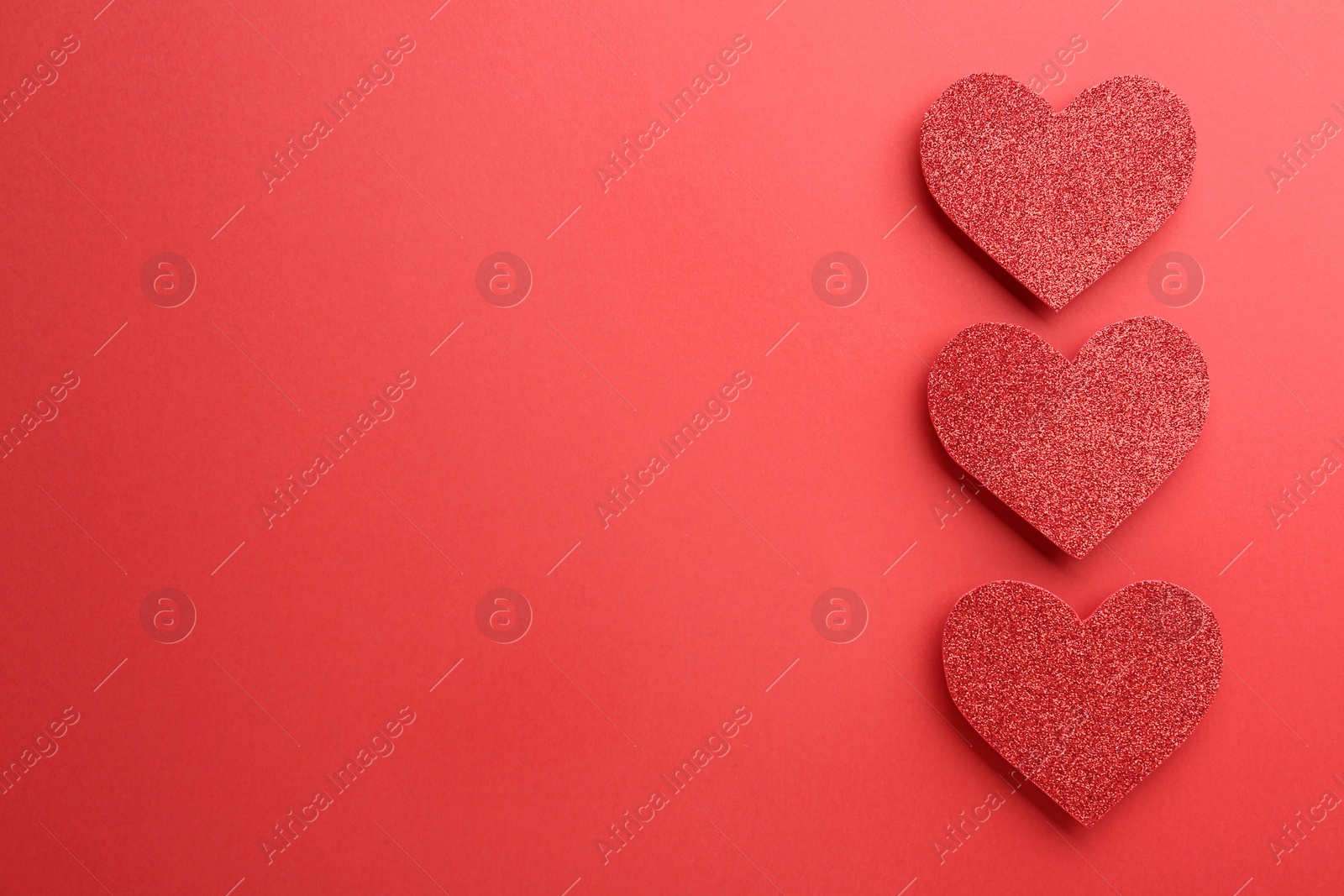 Photo of Shiny paper hearts on red background, flat lay. Space for text