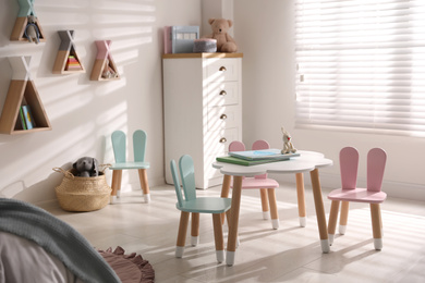 Small table and chairs with bunny ears in children's room interior