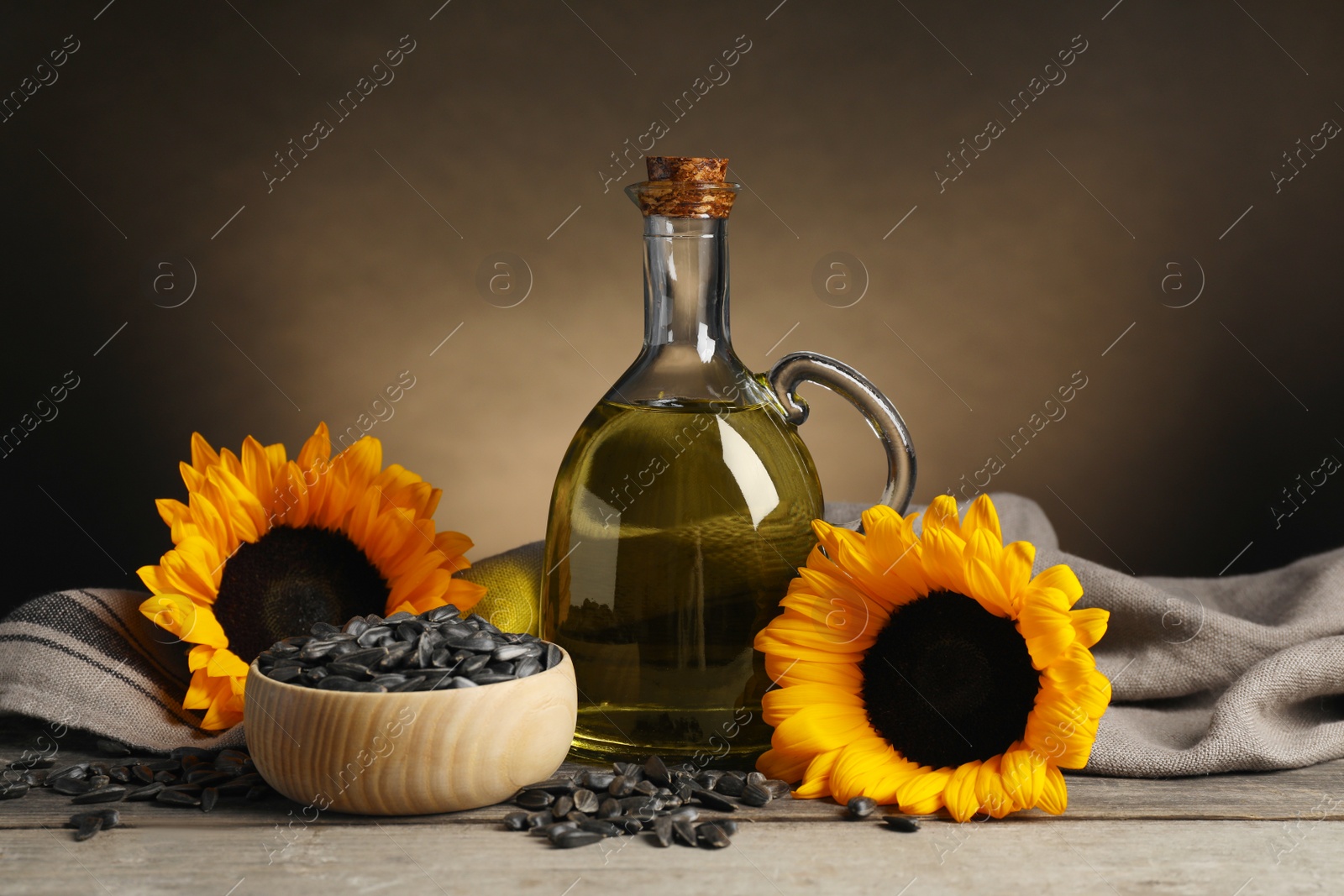 Photo of Sunflower cooking oil, seeds and yellow flowers on light grey table