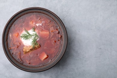 Photo of Tasty borscht with sour cream in bowl on light grey table, top view. Space for text