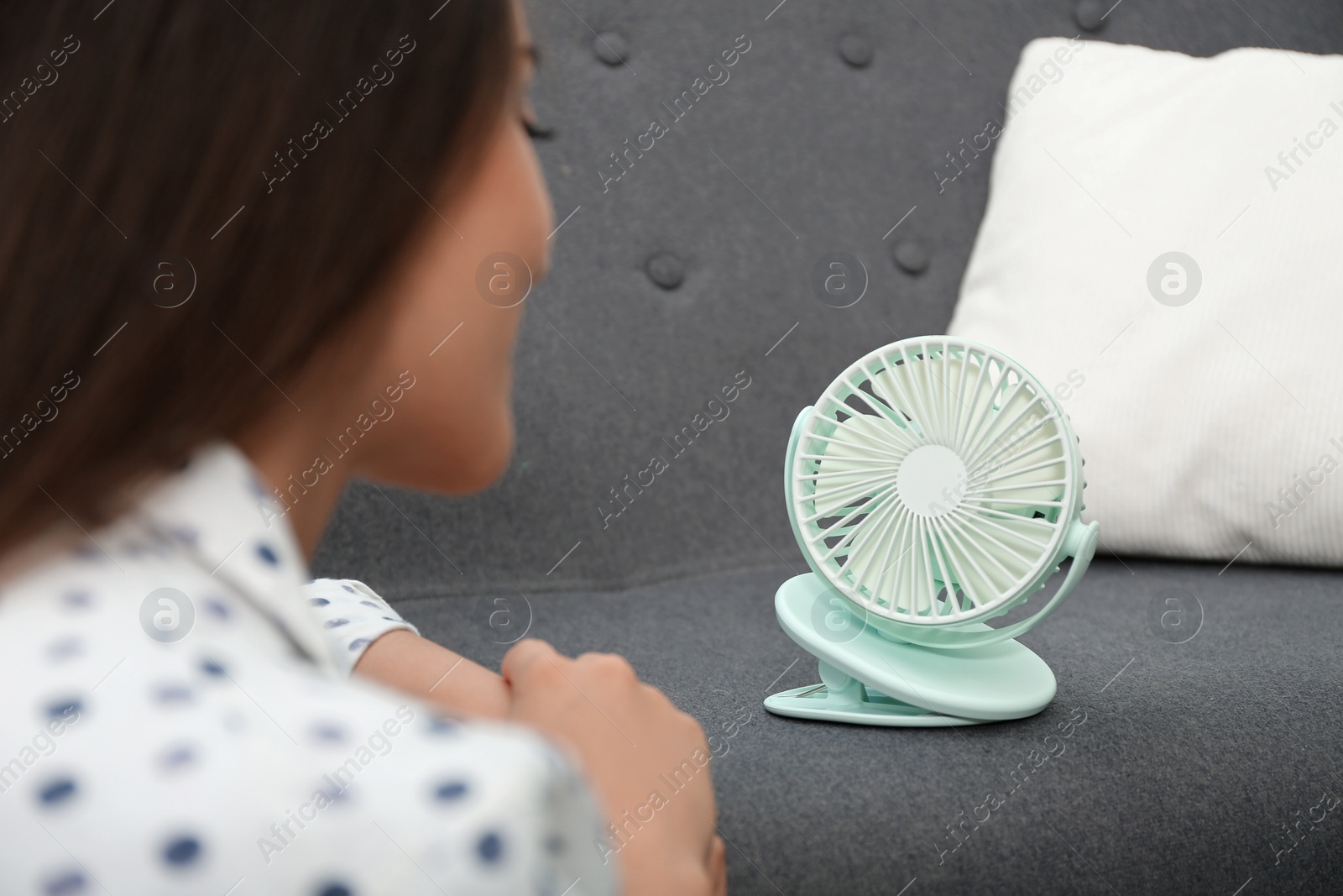 Photo of Woman with portable fan at home. Summer heat