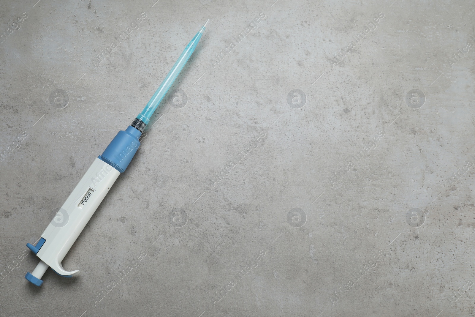 Photo of Laboratory analysis. Micropipette with liquid on grey table, top view. Space for text