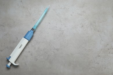 Photo of Laboratory analysis. Micropipette with liquid on grey table, top view. Space for text