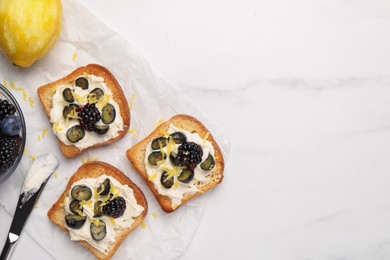 Photo of Tasty sandwiches with cream cheese, blueberries, blackberries and lemon zest on white marble table, flat lay. Space for text