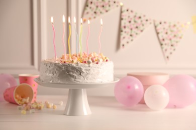 Photo of Tasty Birthday cake with burning candles and party decor on white table, space for text