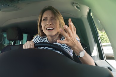 Photo of Stressed angry woman in driver's seat of modern car, view through windshield